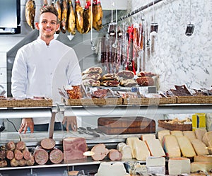 Shop-boy in special clothing shifting sausage