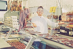 Shop-boy in special clothing shifting sausage