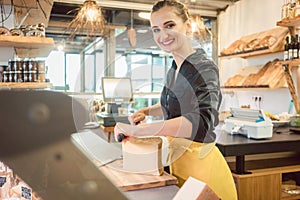 Shop clerk in deli cutting cheese