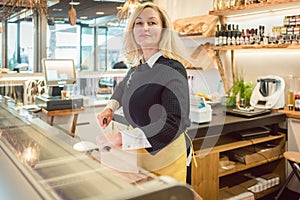 Shop clerk in deli cutting cheese