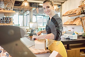 Shop clerk in deli cutting cheese photo