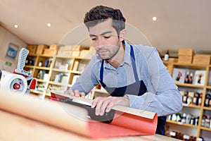 Shop clerk wrapping bottle wine