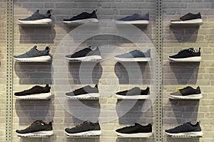 Shop display of unbranded modern new stylish sneakers running shoes for men on brick wall background texture