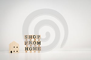 Shop from home message on wooden dices and house wooden model with clean background. Online shopping online or shopping at home