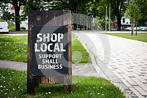 Shop Local. Support small business. Wooden billboard on the street, sunny day