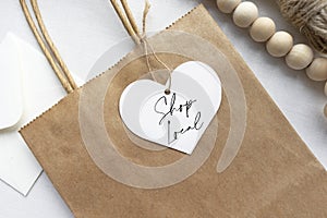 `Shop local` text on a gift tag and brown paper bag