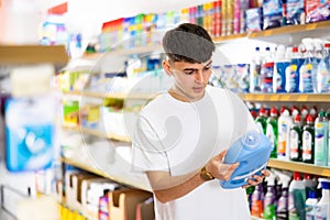 in shop, man chooses detergent for dishes.