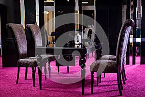 Shop, sale of furniture on the sales area. Dining table is black glossy color with barchannyh four chairs on a mirror background a