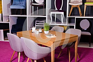 Shop, sale of furniture in a shopping center. Exposition sample Dining wooden table with textile chairs in gray on a white shelf w