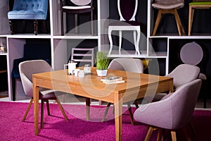 Shop, sale of furniture in a shopping center. Exposition sample Dining wooden table with textile chairs in gray on a white shelf w