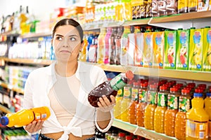 in shop, smiling girl chooses drink.