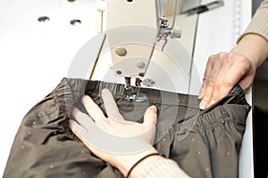 Shop for tailoring. A woman creates clothes on a sewing machine. Fashion industry for people. Stylish fashionista woman