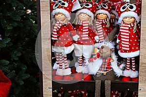Shop window with Christmas and New Year`s toys and decorations. Funny dolls in santa claus hats on a shelf of a toy store.
