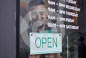 Shop, window and happy businessman open with sign for working time in retail, store or service in small business