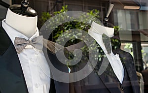 Shop window of mens tailor shop showing 2 mannequins in tuxedos. photo