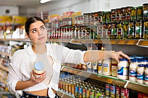 in shop, woman chooses mayonnaise.