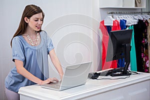 Shop worker using laptop by the till