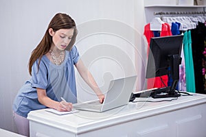 Shop worker using laptop by the till