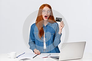 Shopaholic excited buy new things online. Thrilled and shook good-looking redhead female holding credit card look amused