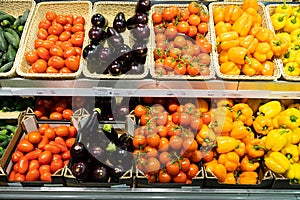 Shopboard counter with wicker baskets and lug boxes with tomatoes, squash, orange and yellow pepper and eggplant
