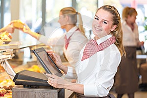 Shopkeeper at bakery working at cash register