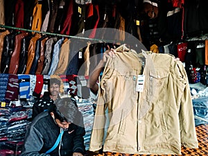 shopkeeper offering jacket during winter season at garment showroom in india dec 2019