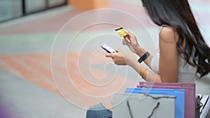 Shopper girl hold credit cards and smartphone in hand with a shopping bag placed on the side