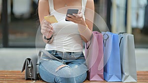 Shopper girl hold credit cards and smartphone in hand with a shopping bag placed on the side