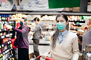 Shopper with mask safely buying for groceries due to coronavirus pandemic in grocery store.COVID-19 shopping.Quarantine