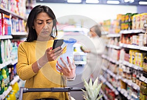 Shopper using smartphone scans qr code on label in supermarket