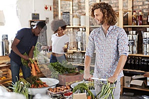 Shoppers Buying Fresh Fruit And Vegetables In Sustainable Plastic Free Grocery Store