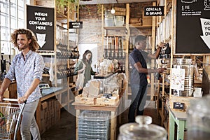 Shoppers In Dried Goods Section Of Sustainable Plastic Free Grocery Store