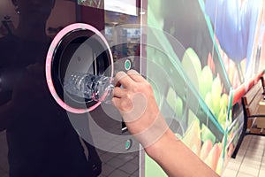 Shoppers return bottles and cans of reusable packagings in a reverse vending machine. Environmental protection concept