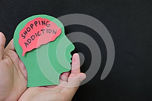 Shopping addiction or shopaholic treatment and how to deal with concept. Hand holding human head profile with shopping word