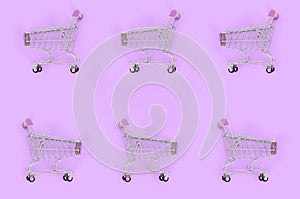 Shopping addiction, shopping lover or shopaholic concept. Many small empty shopping carts perform a pattern on a pastel colored