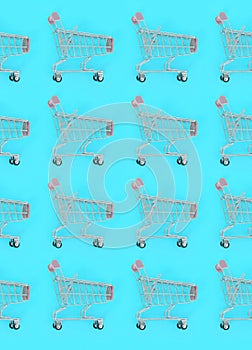 Shopping addiction, shopping lover or shopaholic concept. Many small empty shopping carts perform a pattern on a pastel colored