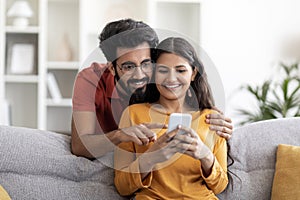 Shopping App. Happy Indian Couple Using Smartphone At Home Together