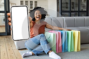 Shopping App. Happy Young Black Woman Demonstrating Blank Smartphone At Home