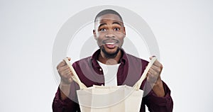 Shopping bag, surprise and face of black man in a studio with sale, discount or promotion. Shock, happy and portrait of