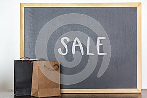 Shopping bags and blackboard on the background with the word Sale. Sale, discount, season sales concept