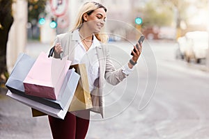 Shopping bags, phone and woman waiting for taxi in city for sale notification, search bargain or internet deal. Fashion
