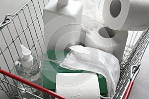 Shopping basket with antiseptics, toilet paper, gloves and masks on grey table. Panic caused by virus