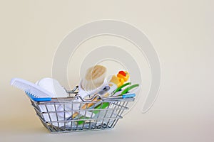 Shopping basket with baby care items - scissors, two hairbrushes, thermometer, cotton pads and nasal aspirator.