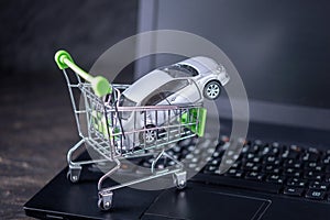 Shopping basket with car on laptop keyboard on dark background. Concept of online shopping vehicles on the Internet