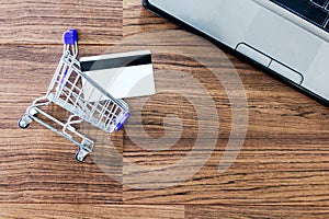 Shopping basket and credit card on wooden background - Online shopping concept