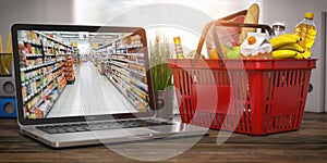 Shopping basket with food and laptop with shelf of supermarket  or grocery shop on the screen. Online ordering and delivery food