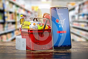 Shopping basket with fresh food and smartphone. Grocery supermarket, food and eats online buying and delivery concept photo