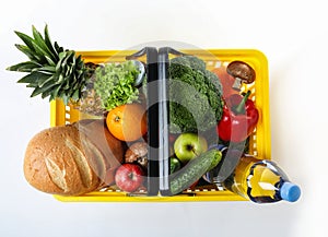 Shopping basket with grocery products on white, top view