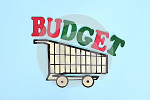 Shopping budget concept. Wooden shopping cart with word in blue background.