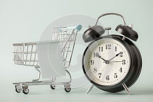 Shopping cart and alarm clock on blue background